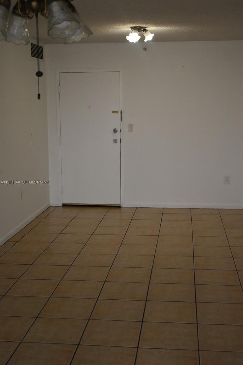 A room with beige tile flooring, a white door, and a ceiling light fixture — 616 NW 26th Ave # 210, Miami FL 33125, MIAMI, FL