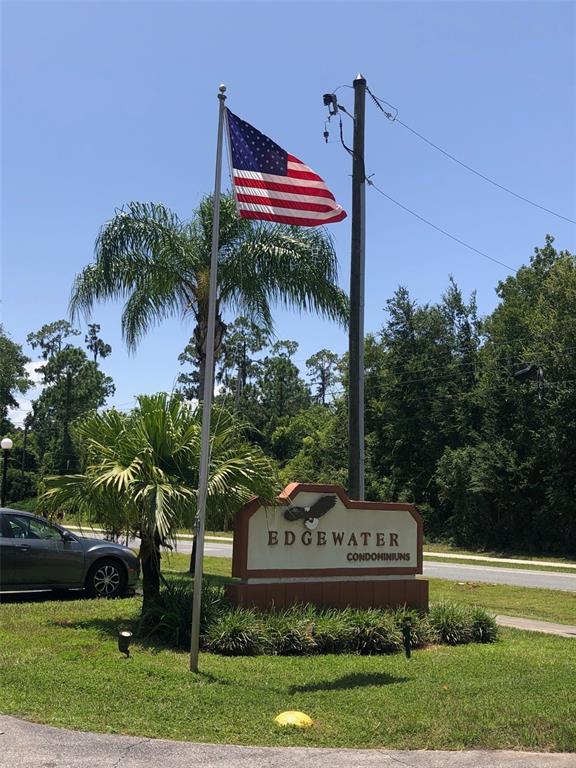 A sign for Edgewater Condominiums stands next to a flagpole with an American flag — 170 PALMETTO WOODS COURT UNIT 3C, DELTONA, FL