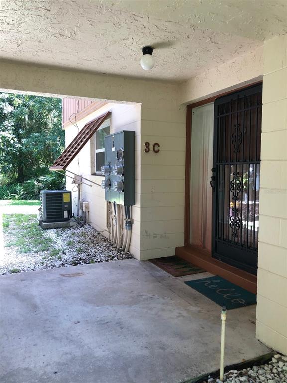 A concrete patio area features a unit entrance with a security door and utility meters — 170 PALMETTO WOODS COURT UNIT 3C, DELTONA, FL