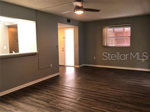 A living room with dark wood-look flooring, a ceiling fan, and a pass-through kitchen window — 170 PALMETTO WOODS COURT UNIT 3C, DELTONA, FL