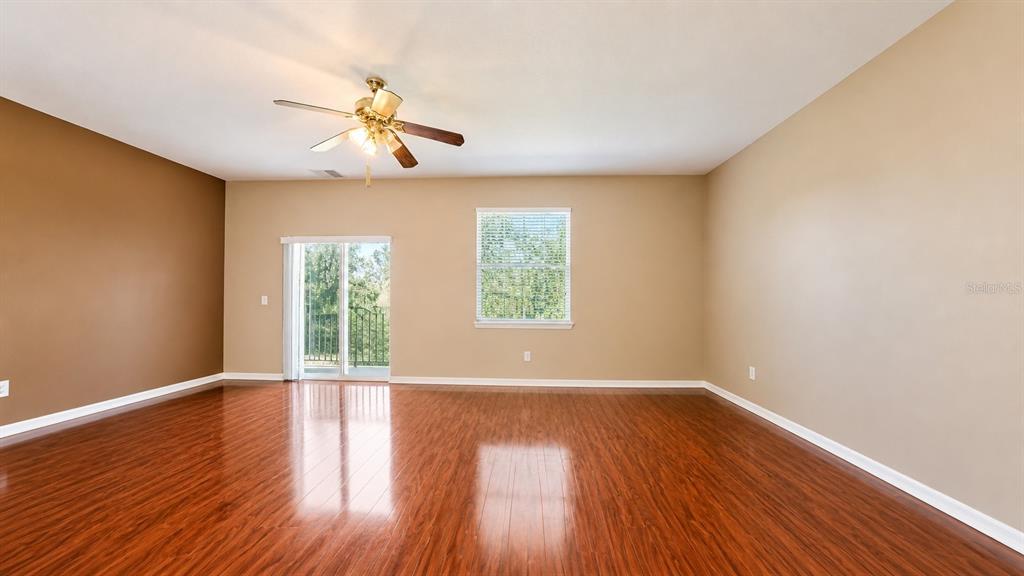 An empty room features wood-look flooring, a ceiling fan, a window, and sliding glass doors — 4116 ORANGE TREE COURT, ST CLOUD, FL