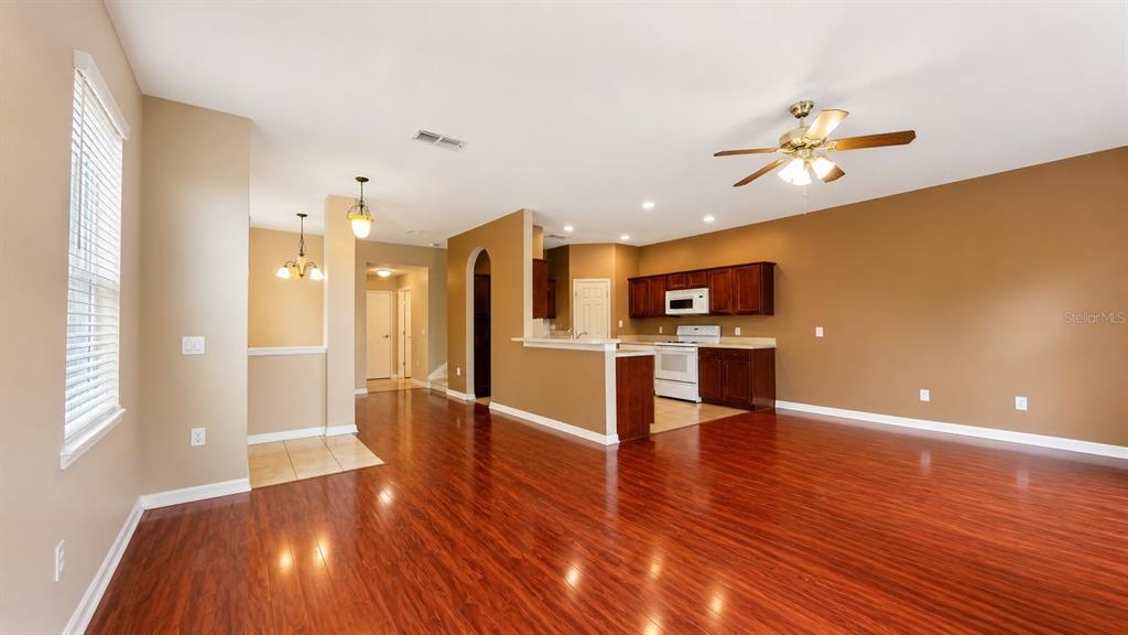 A living room with hardwood floors opens to a kitchen with dark wood cabinets — 4116 ORANGE TREE COURT, ST CLOUD, FL