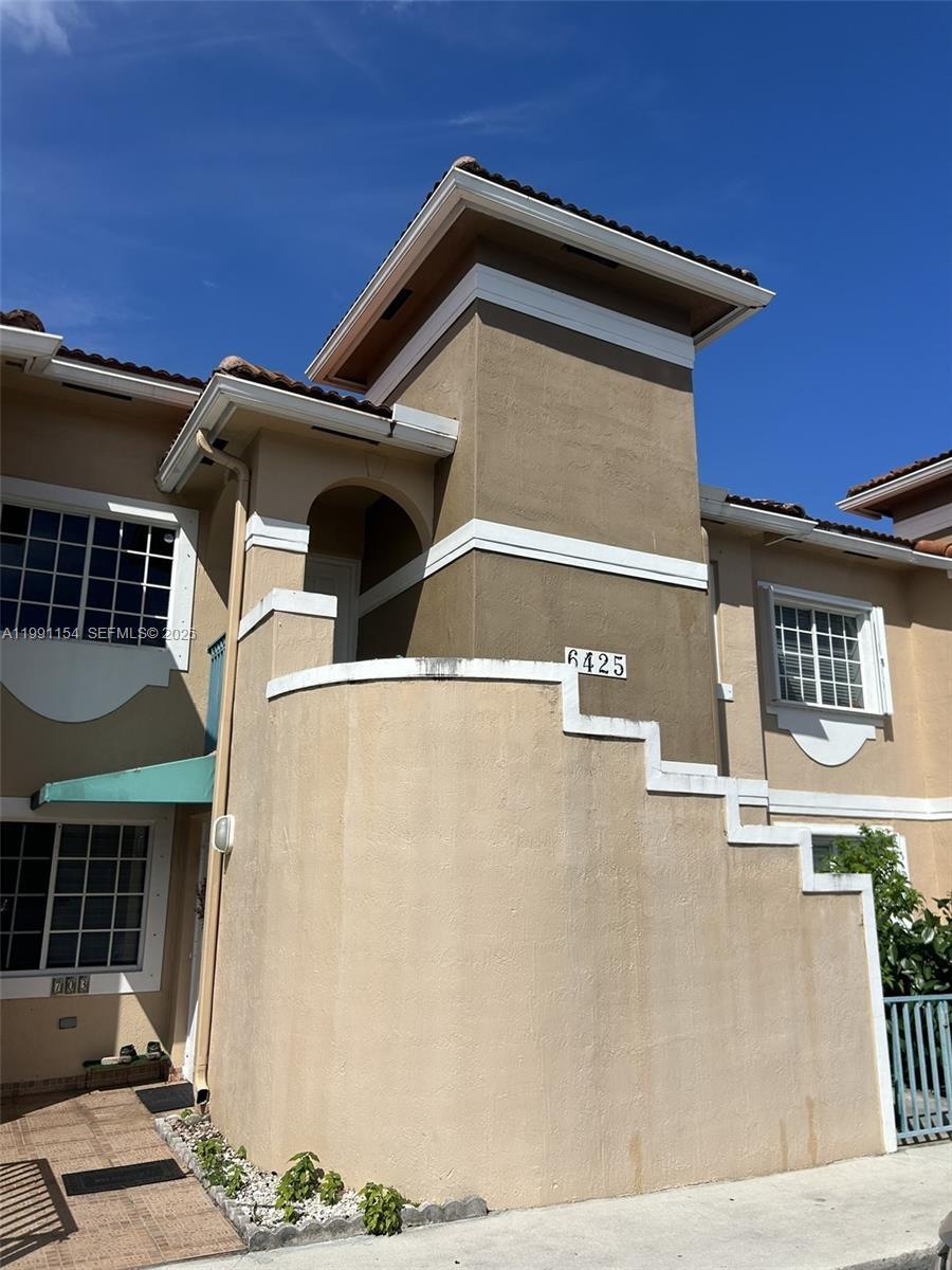 A two-story tan stucco townhouse exterior features a prominent tower section and a staircase — 6425 SW 130th Pl # 704, Miami FL 33183, MIAMI, FL