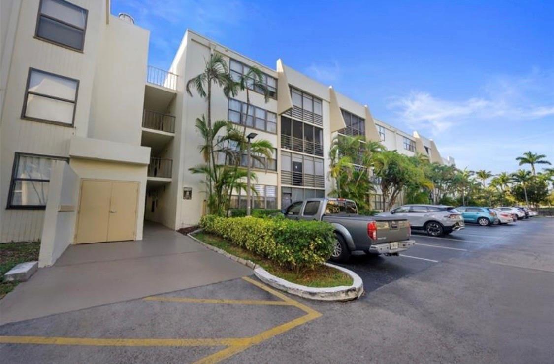 A multi-story apartment building with a parking lot and palm trees in front — 20441 NE 30th Avenue # 9, Miami FL 33180, MIAMI, FL