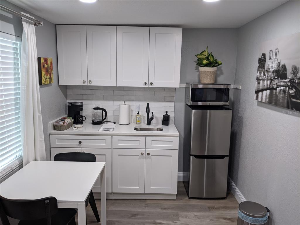 A small kitchenette features white cabinets, a stainless steel refrigerator, and a white dining table — 4538 W MINNEHAHA STREET UNIT B, TAMPA, FL