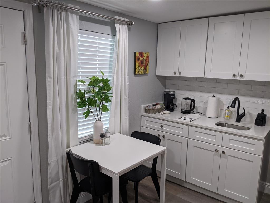 A small kitchen area features white cabinets, a sink, and a dining table with chairs — 4538 W MINNEHAHA STREET UNIT B, TAMPA, FL