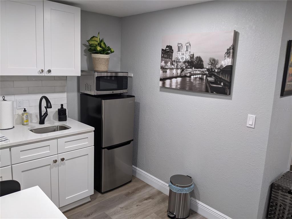A small kitchen features white cabinets, a stainless steel refrigerator, and a black-and-white wall print — 4538 W MINNEHAHA STREET UNIT B, TAMPA, FL