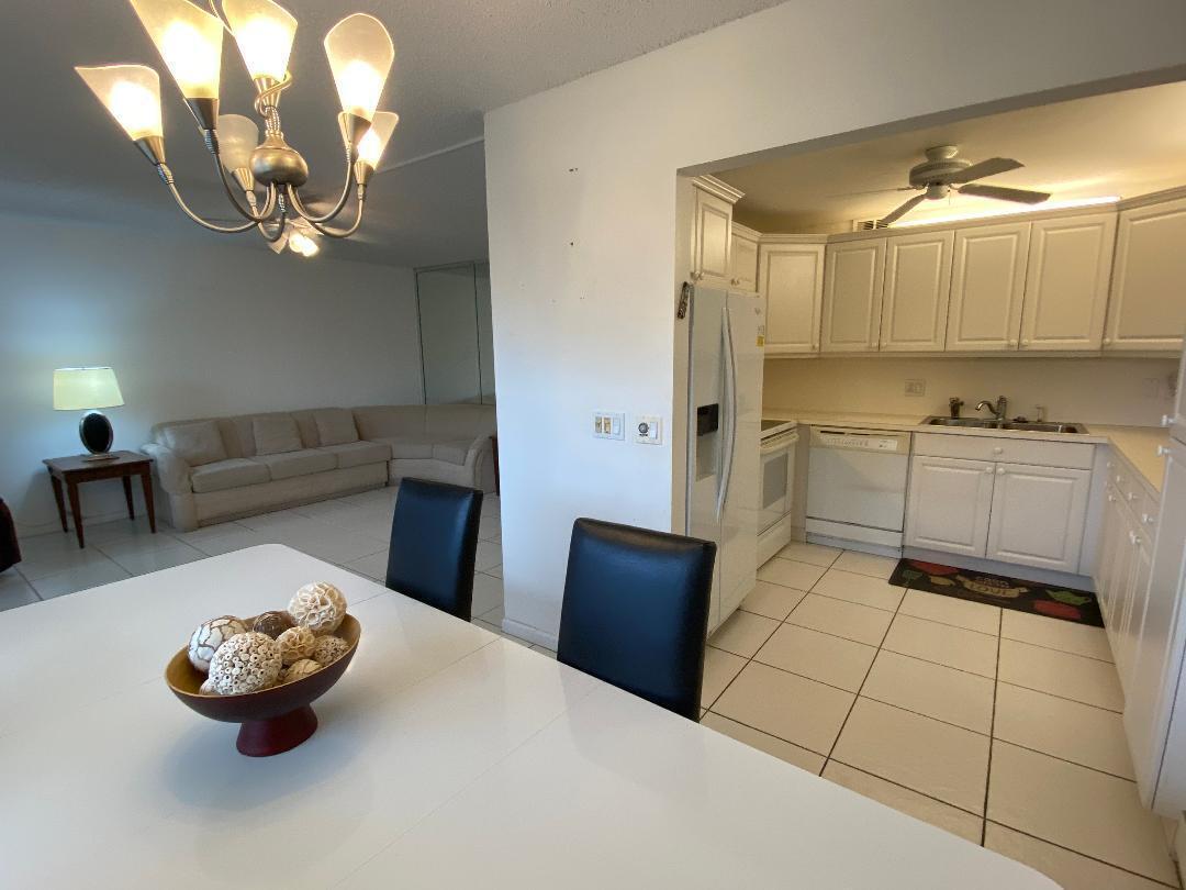 A dining area with a chandelier overlooks a living room and an adjacent white kitchen — 3043 Berkshire C, Deerfield Beach FL 33442, DEERFIELD BEACH, FL