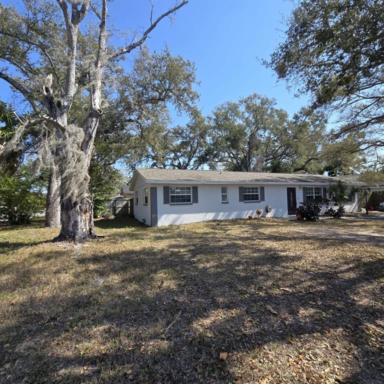 A single-story house with a white exterior and gray shutters sits on a grassy lot — 1021 FAIRBURN AVENUE, CLEARWATER, FL