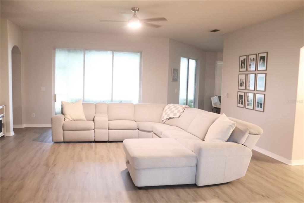 A living room features a large light-colored sectional sofa on wood-look flooring — 3850 BEACON RIDGE WAY, CLERMONT, FL