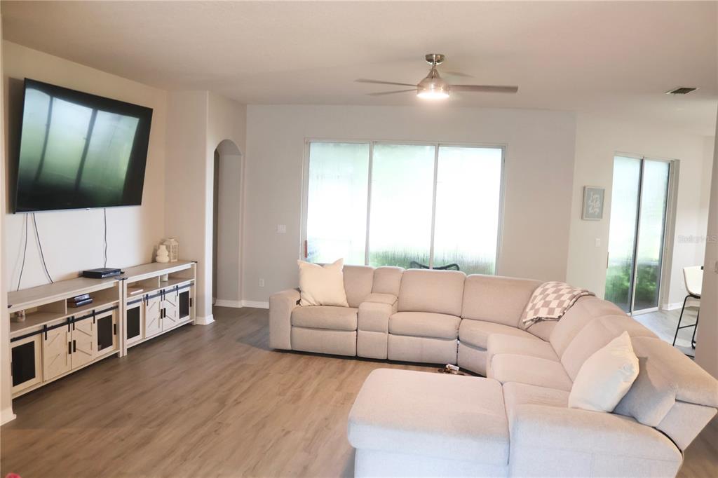 A living room features a large sectional sofa, a television, and a media console — 3850 BEACON RIDGE WAY, CLERMONT, FL
