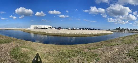 A panoramic view of a retention pond bordering a parking area with a white structure — 6723 SOLSTICE DRIVE, TITUSVILLE, FL