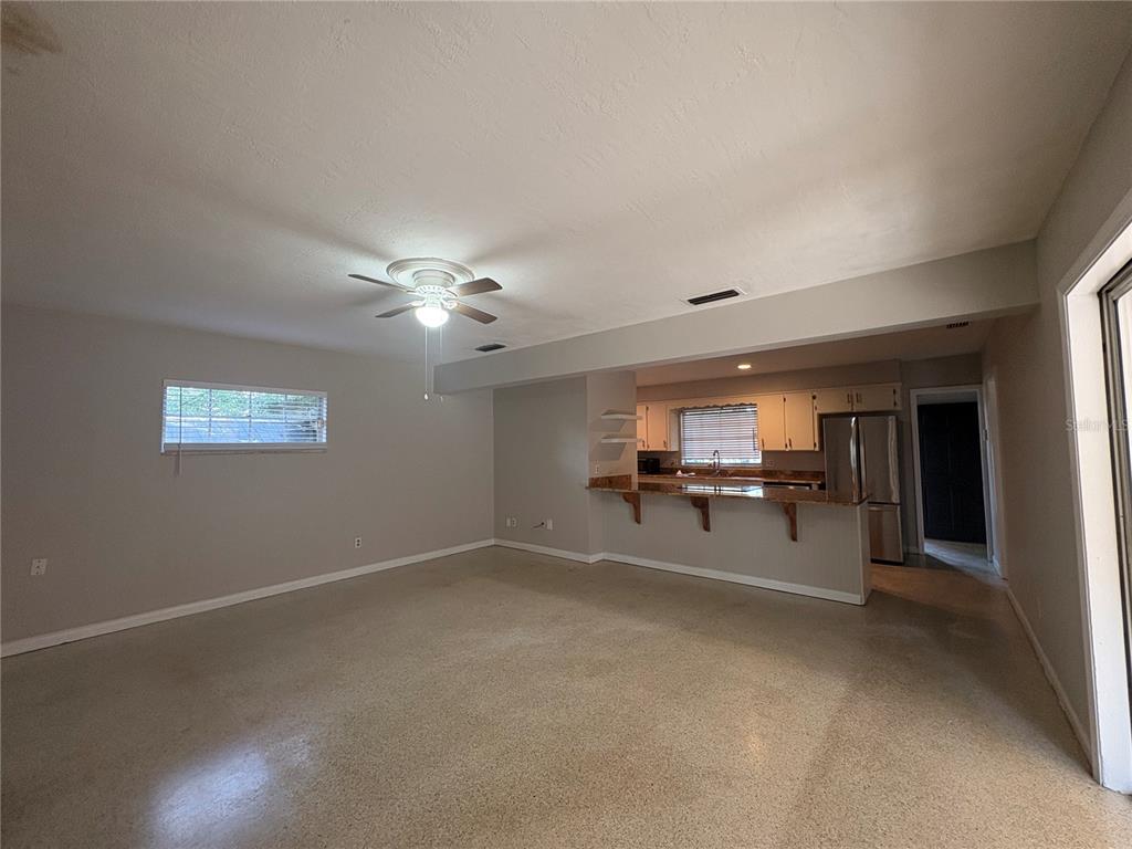 An open-concept living room features a ceiling fan, neutral walls, and a kitchen breakfast bar — 719 KEWANNEE TRAIL, MAITLAND, FL