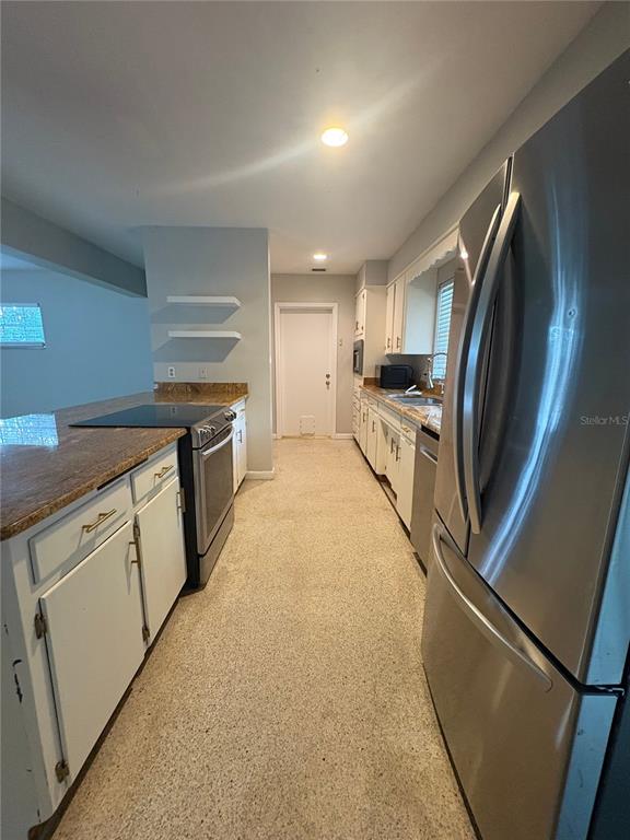 A galley kitchen features white cabinets, granite countertops, stainless steel appliances, and terrazzo flooring — 719 KEWANNEE TRAIL, MAITLAND, FL