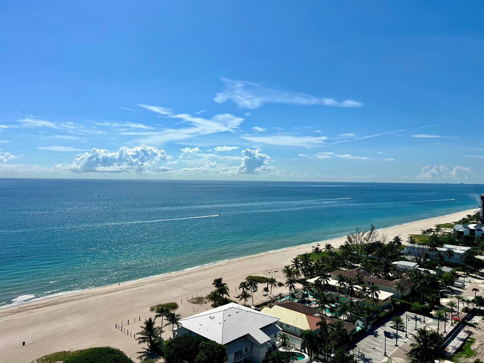 An elevated view of a sandy beach, turquoise ocean, and coastal buildings under a blue sky — 111 Briny Avenue # 06, Pompano Beach FL 33062, POMPANO BEACH, FL