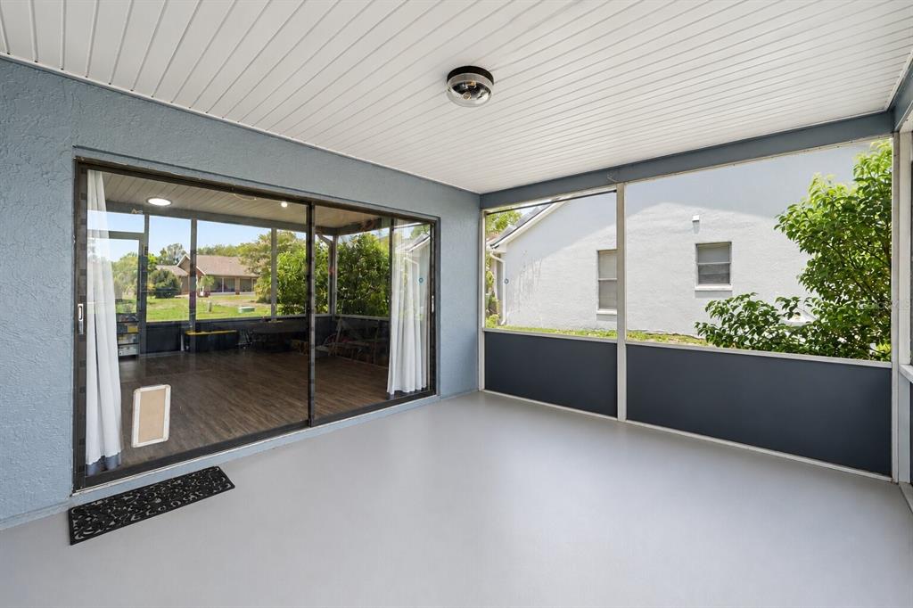A covered patio features gray flooring, blue walls, a ceiling light, and sliding glass doors — 9074 HEATHER BOULEVARD, WEEKI WACHEE, FL