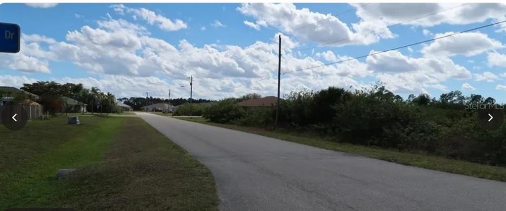 A paved road runs through a residential area with grassy lots and scattered trees — 836 NEUSE AVENUE, FORT MYERS, FL