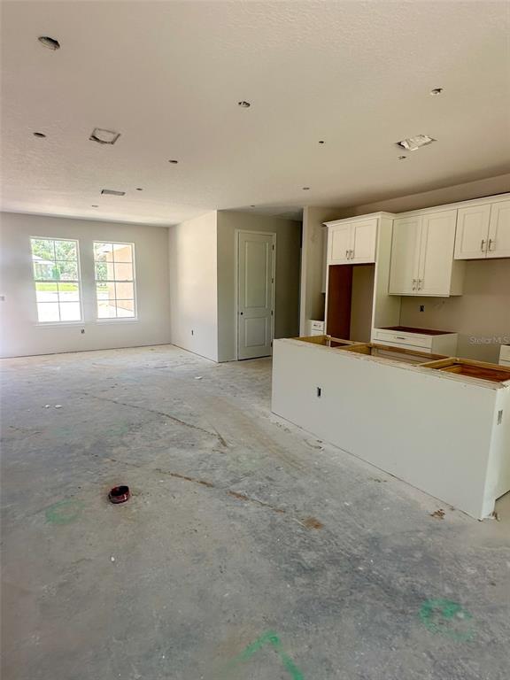 An unfinished kitchen and living area feature white cabinets, a central island, and concrete floors — 5784 N DURANGO TERRACE, BEVERLY HILLS, FL
