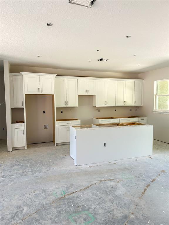 A kitchen under construction features white cabinets, a central island, and unfinished flooring — 5784 N DURANGO TERRACE, BEVERLY HILLS, FL