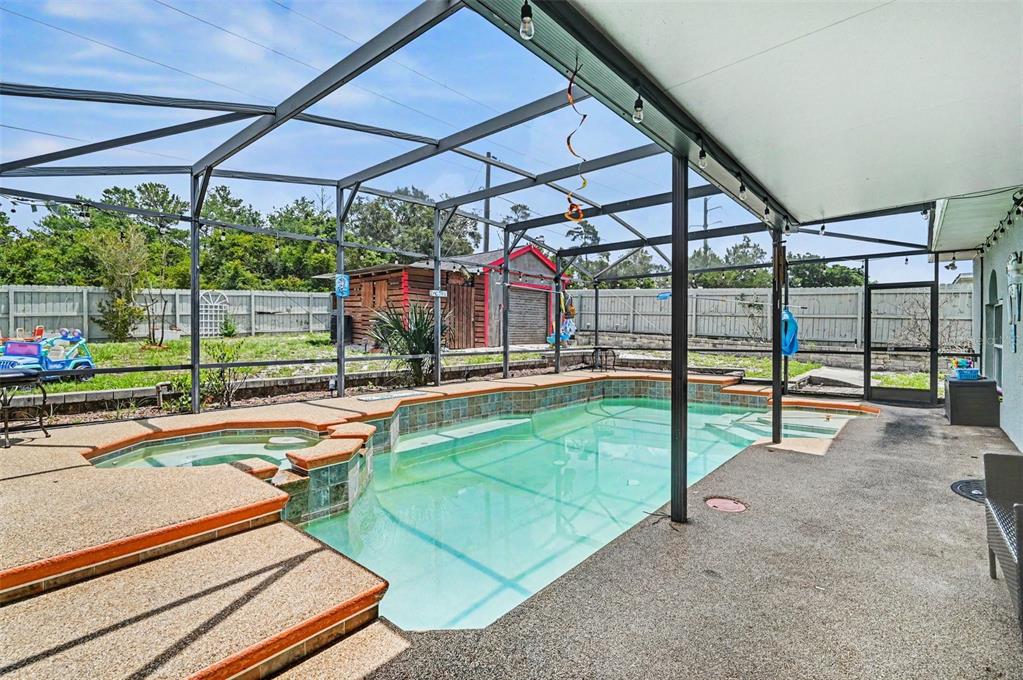 A screened-in patio features a swimming pool, a hot tub, and outdoor seating — 614 N FIRWOOD DRIVE, DELTONA, FL