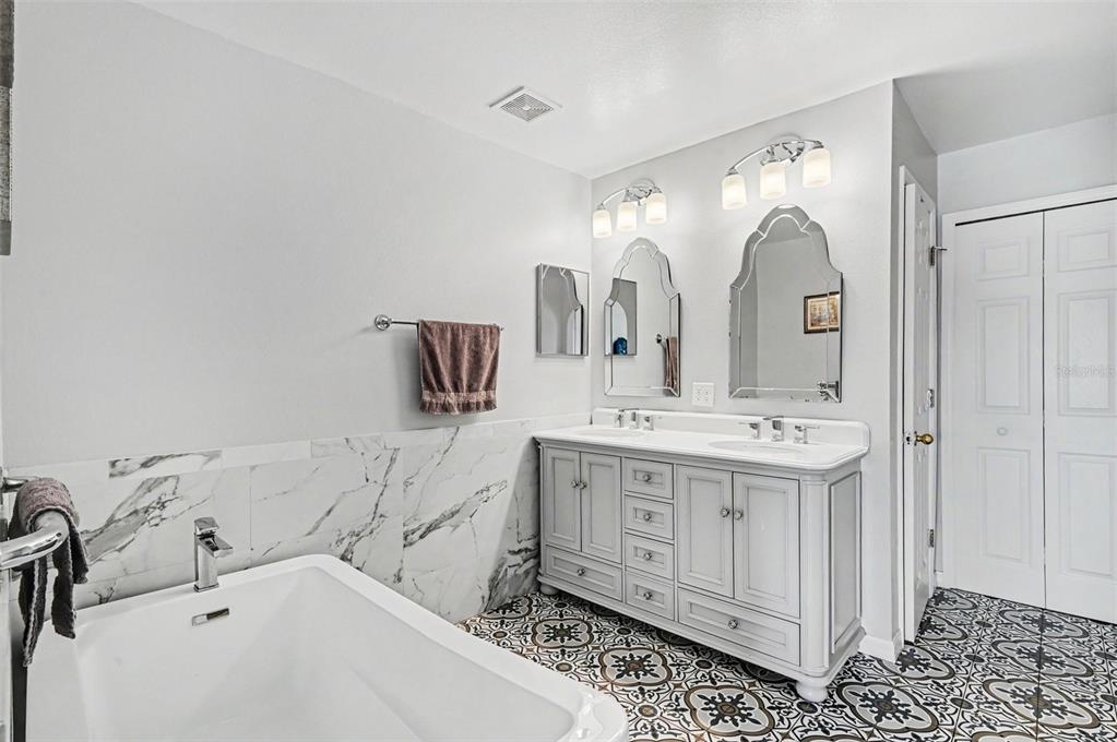 A bathroom features a toilet, a wall-mounted cabinet, and a walk-in shower with marble tile — 614 N FIRWOOD DRIVE, DELTONA, FL