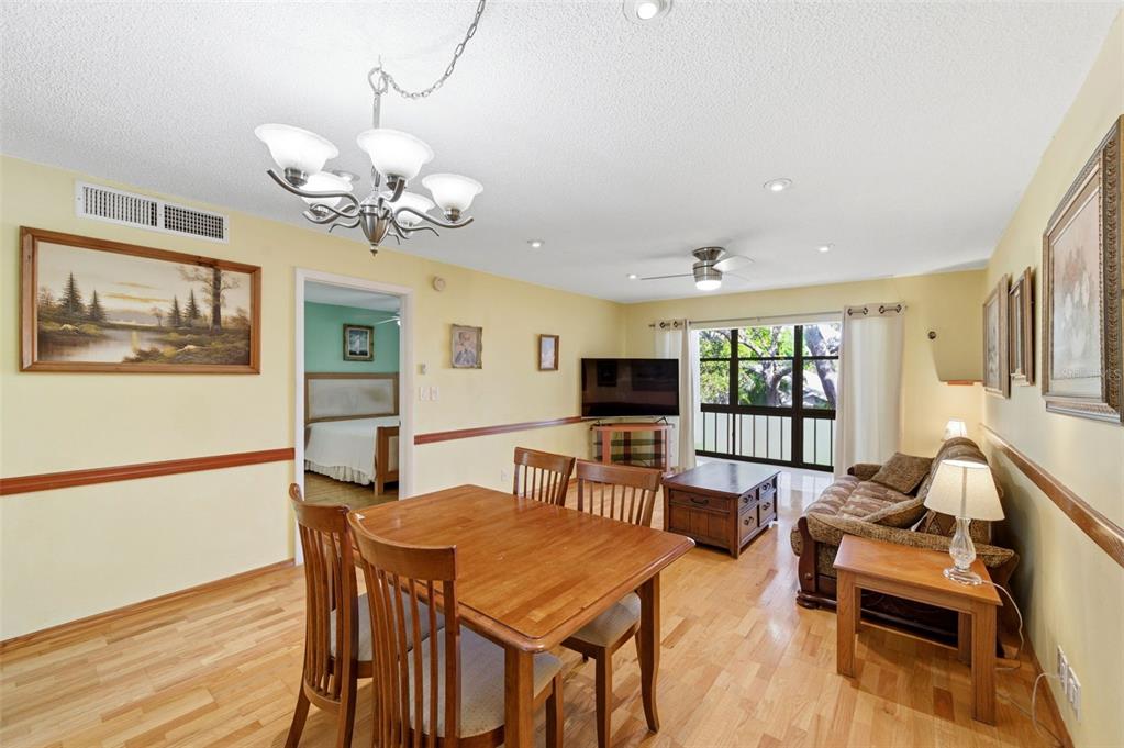 A dining area and living room with wood floors, a chandelier, and a sliding glass door — 11485 OAKHURST ROAD UNIT 200-208, LARGO, FL