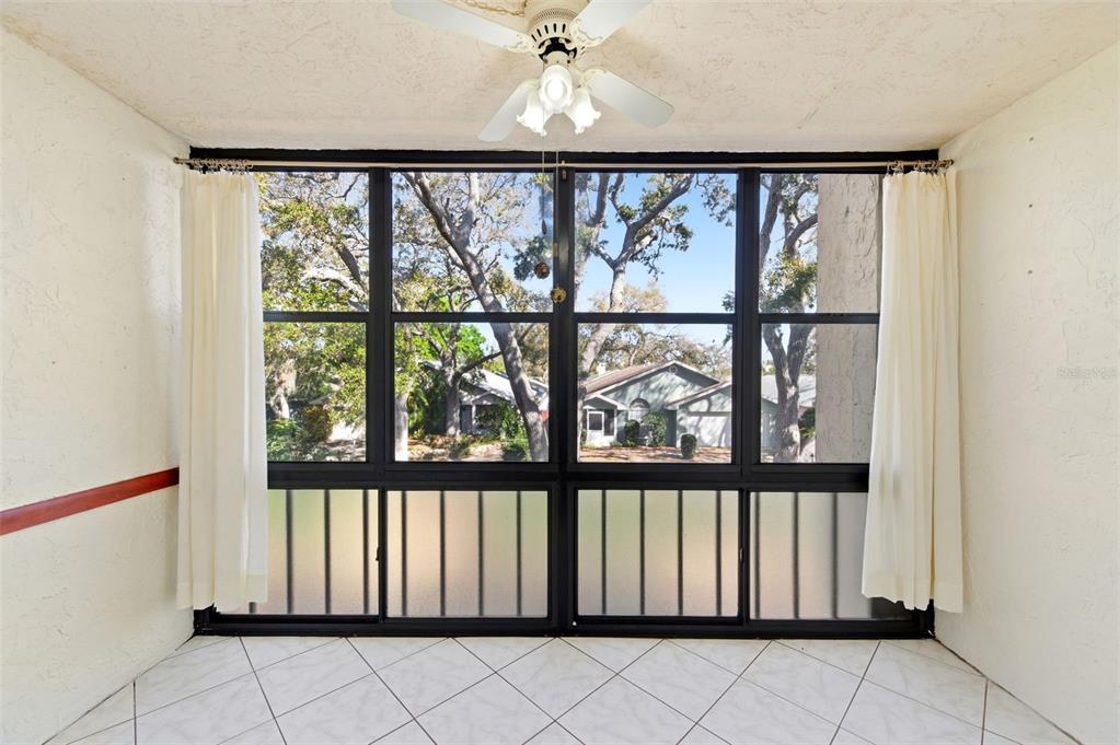 A sunroom with white tile floors, a ceiling fan, and large windows overlooking a neighborhood — 11485 OAKHURST ROAD UNIT 200-208, LARGO, FL