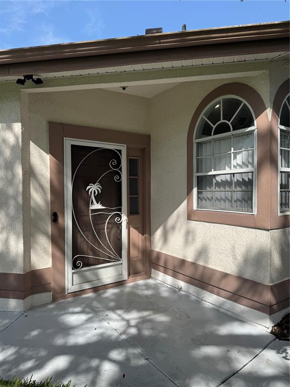 A front entryway features a decorative screen door with a palm tree design and stucco walls — 5754 PARKVIEW LAKE DRIVE, ORLANDO, FL
