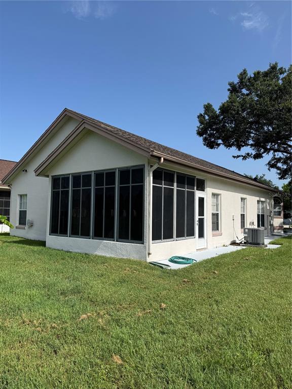 A side view of a house featuring a large screened-in porch and a grassy yard — 5754 PARKVIEW LAKE DRIVE, ORLANDO, FL
