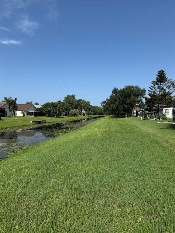 A grassy backyard leads to a narrow canal bordered by residential houses and trees — 5754 PARKVIEW LAKE DRIVE, ORLANDO, FL