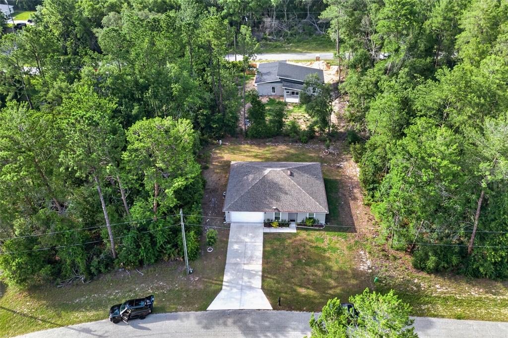 An aerial view shows a single-story house with a concrete driveway surrounded by dense trees — 8257 SW 129TH PLACE, OCALA, FL