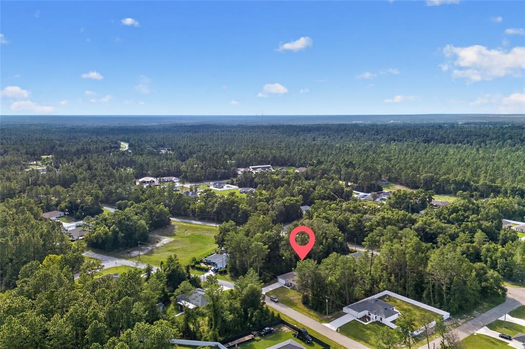 An aerial view shows a house nestled among dense trees in a rural residential area — 8257 SW 129TH PLACE, OCALA, FL