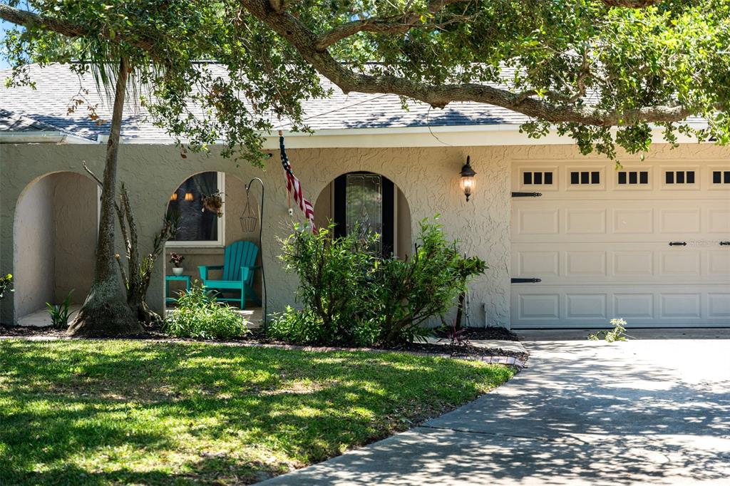 A single-story house with a beige stucco exterior, arched entryways, a garage, and a front lawn — 1245 LESLIE DRIVE, MERRITT ISLAND, FL