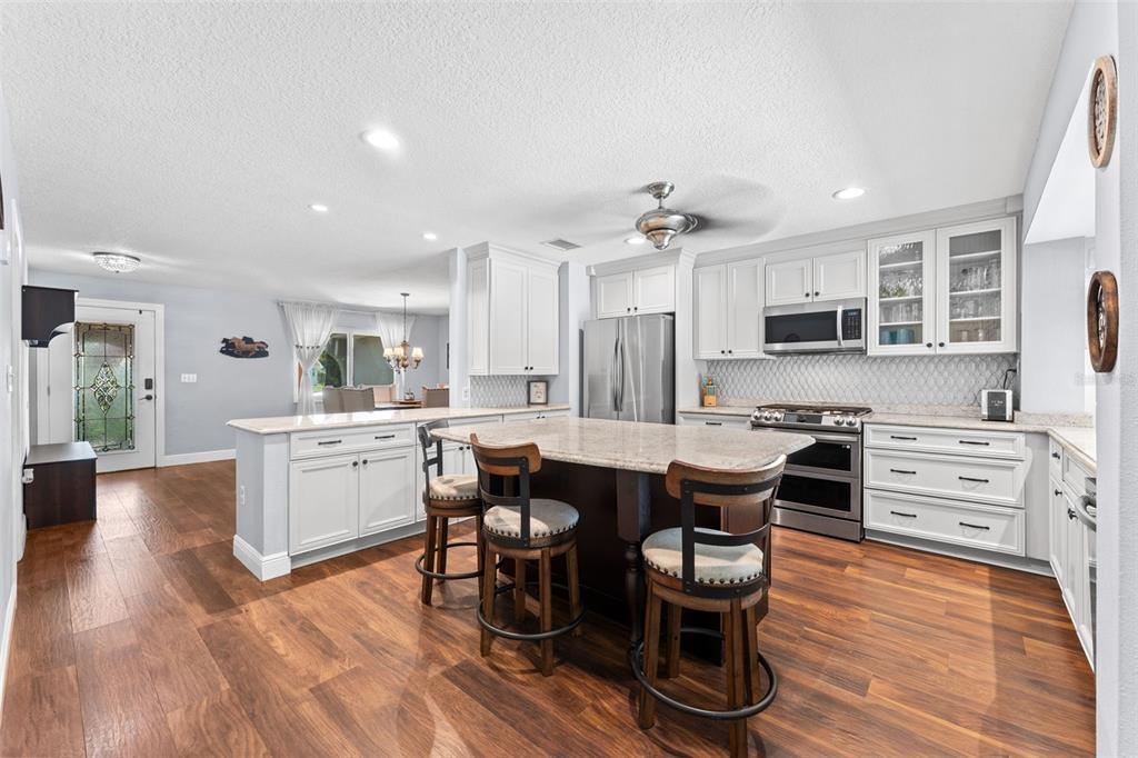 A kitchen with white cabinets, a dark wood island, stainless steel appliances, and wood flooring — 1245 LESLIE DRIVE, MERRITT ISLAND, FL