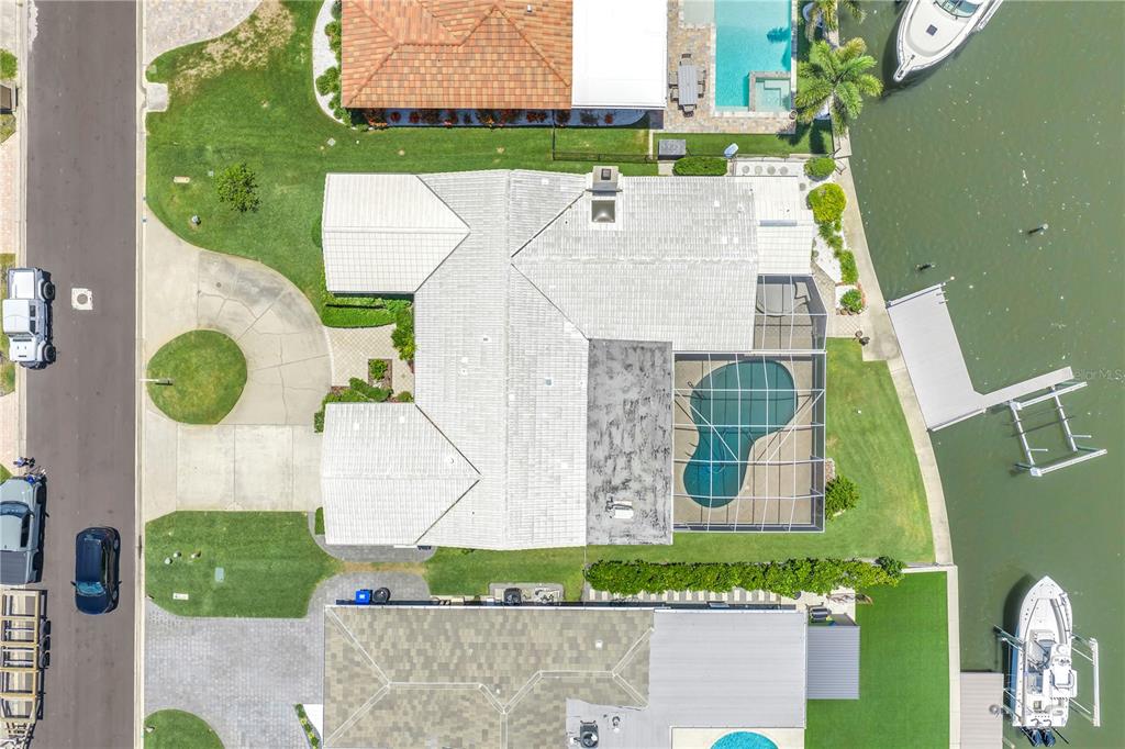An aerial view shows a waterfront house with a pool, screened lanai, and boat dock — 2067 MASSACHUSETTS AVENUE NE, ST PETERSBURG, FL