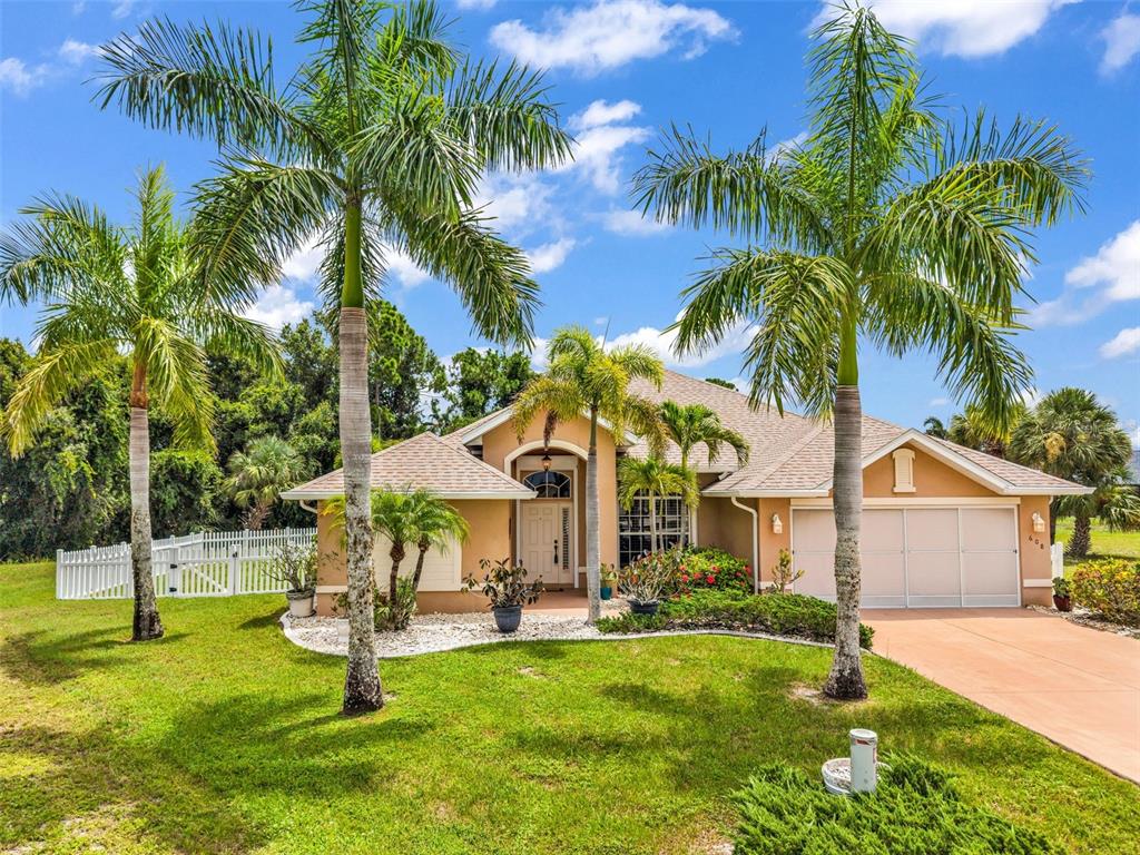 A single-story house with a tan exterior, a two-car garage, and several palm trees — 608 TRUMPET TREE, PUNTA GORDA, FL