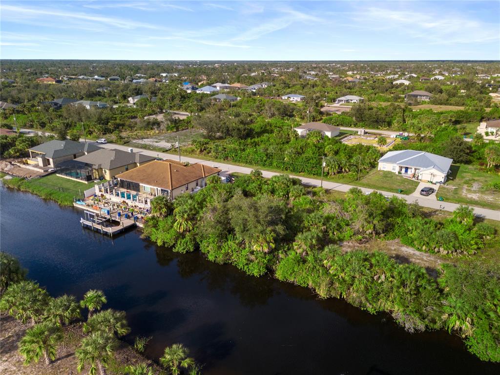 An aerial view shows a canal-front house with a pool deck and dock in Florida — 13886 ALLAMANDA CIRCLE, PORT CHARLOTTE, FL