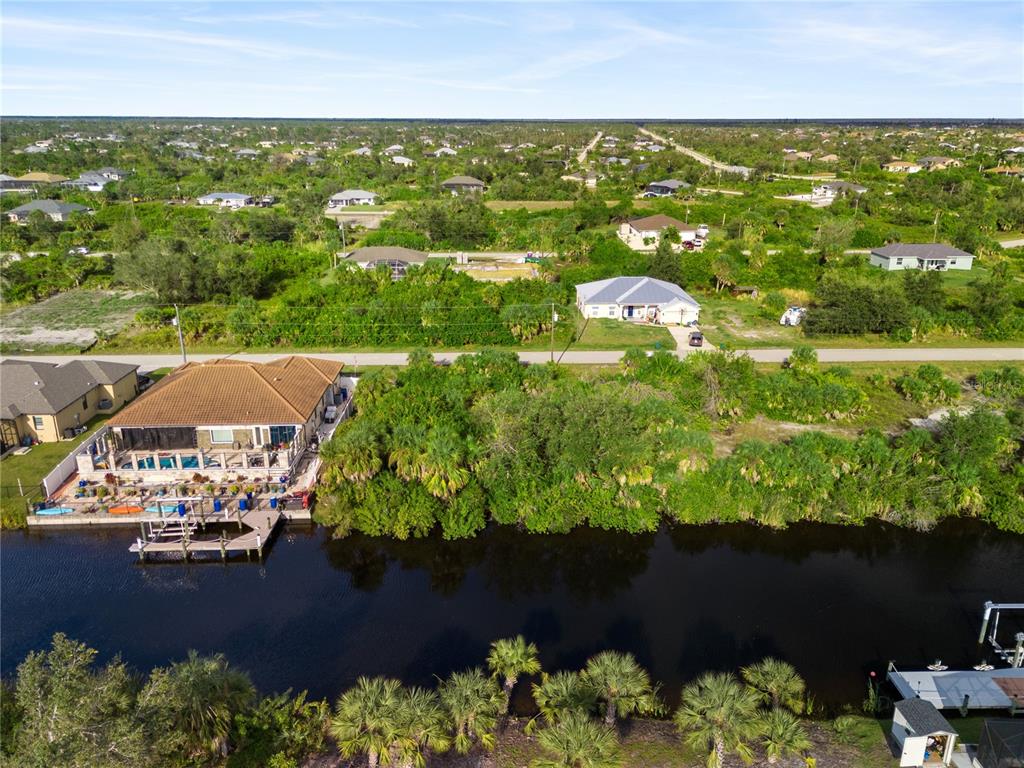 An aerial view shows a waterfront house with a pool deck and dock along a canal — 13886 ALLAMANDA CIRCLE, PORT CHARLOTTE, FL