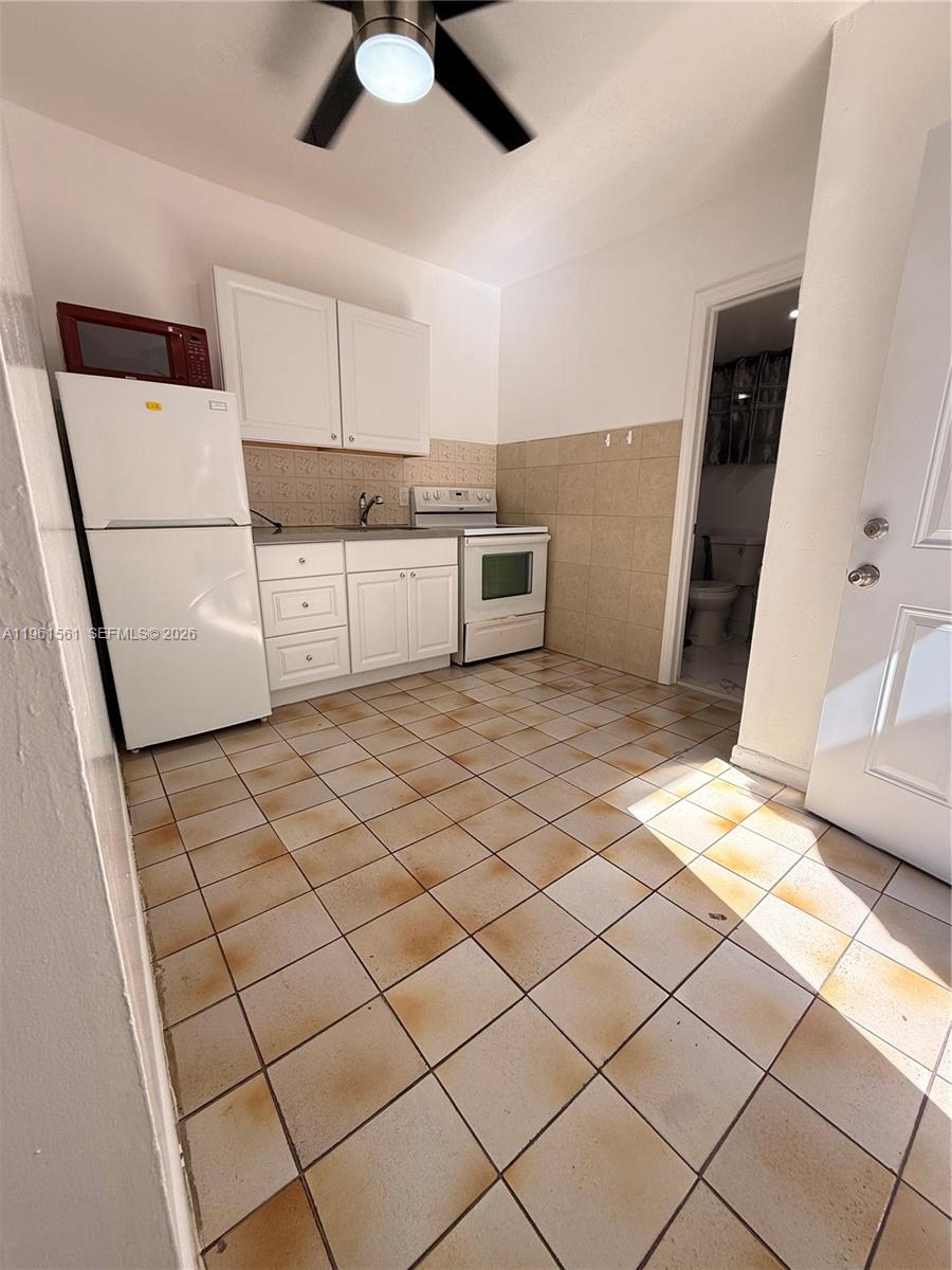 This kitchen features white cabinets, a refrigerator, a stove, and stained tile flooring — 1037 SW 20th Ave # 2, Miami FL 33135, MIAMI, FL
