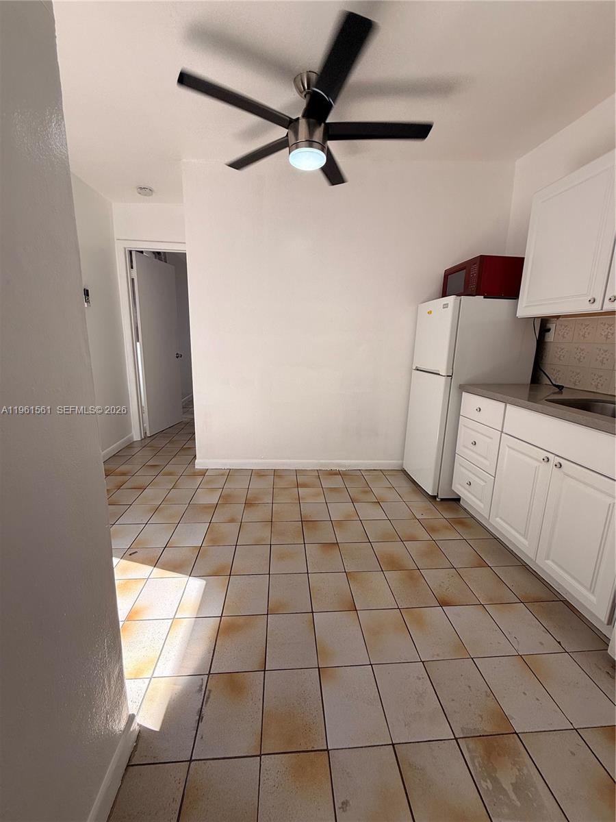 A kitchen features white cabinets, a white refrigerator, and stained light-colored floor tiles — 1037 SW 20th Ave # 2, Miami FL 33135, MIAMI, FL