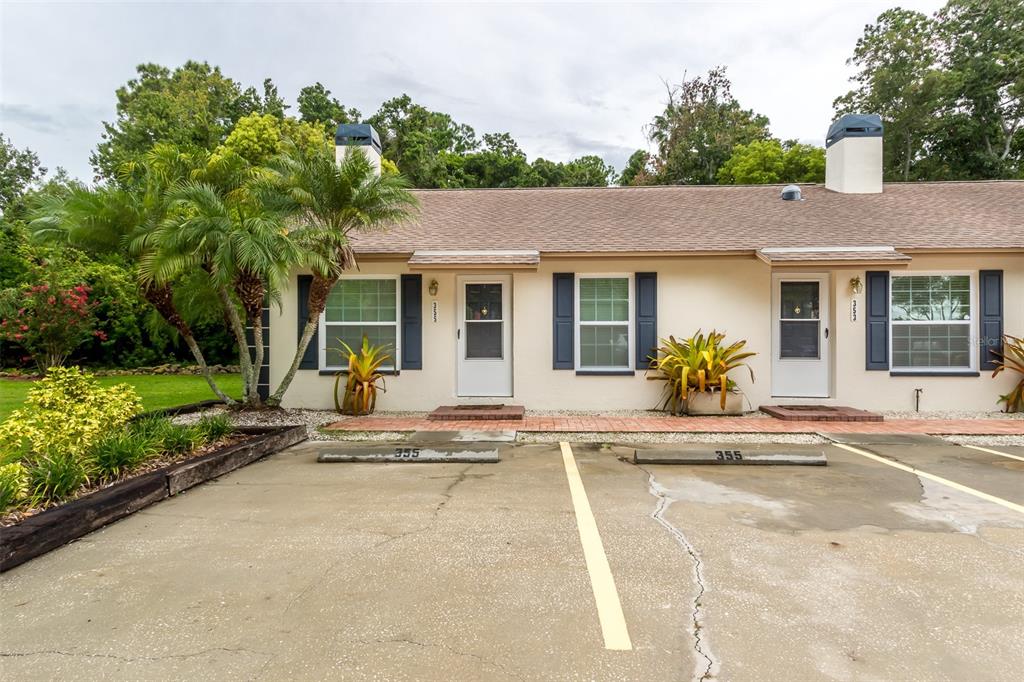 A single-story duplex with a concrete parking area, palm trees, and beige exterior walls — 355 23RD AVENUE SW, SEMINOLE, FL