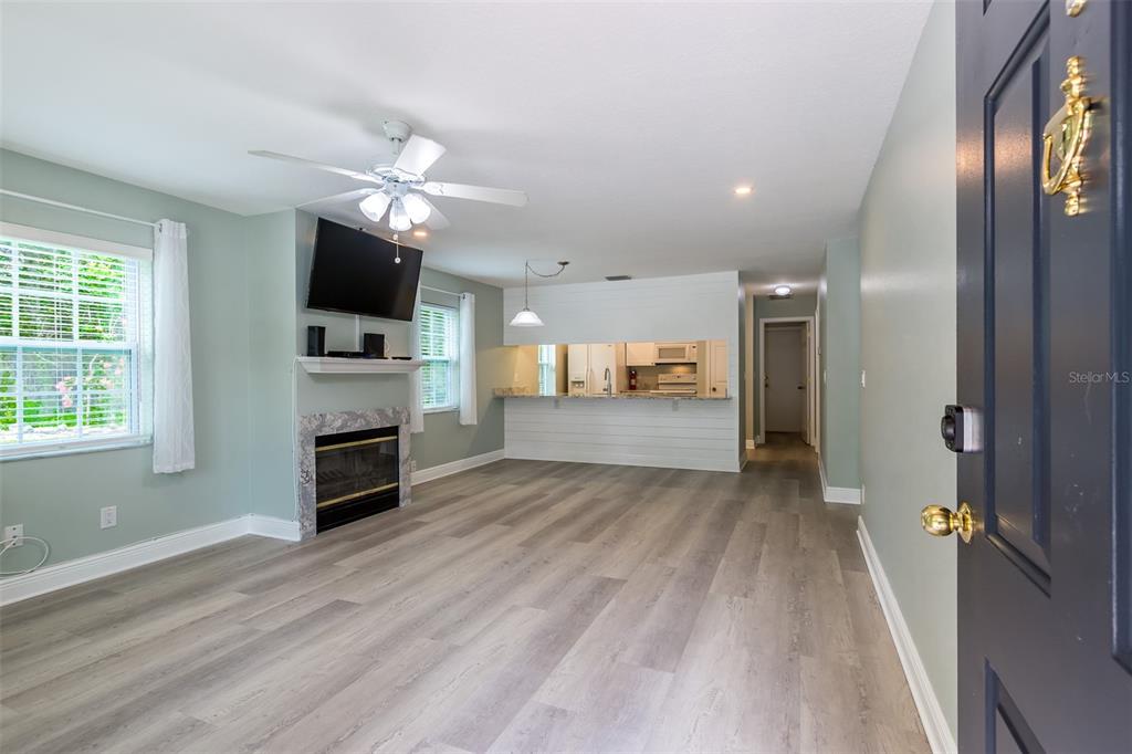 A living room features light wood flooring, a fireplace with a television, and a kitchen pass-through — 355 23RD AVENUE SW, SEMINOLE, FL