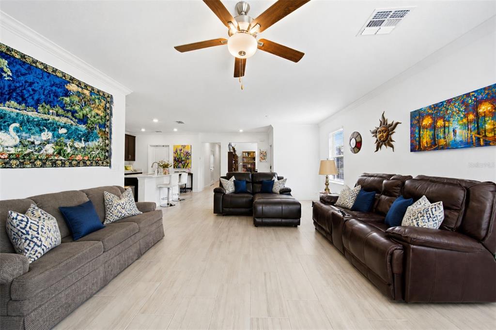A spacious living room features light tile flooring, two brown sofas, and a ceiling fan — 10834 GABLE DIG LOOP, SAN ANTONIO, FL