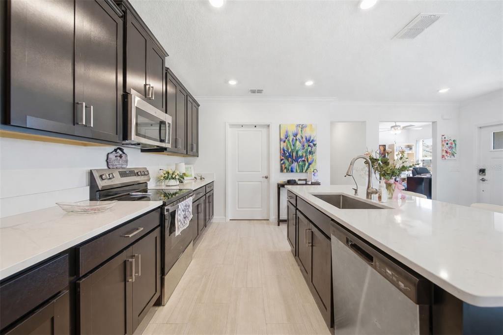 A kitchen features dark wood cabinets, white countertops, stainless steel appliances, and light tile flooring — 10834 GABLE DIG LOOP, SAN ANTONIO, FL