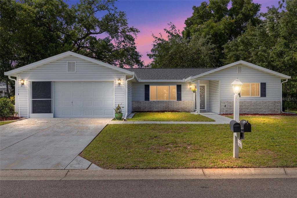 A single-story house with light gray siding, a garage, and a front lawn at dusk — 10622 SE 179TH LANE, SUMMERFIELD, FL