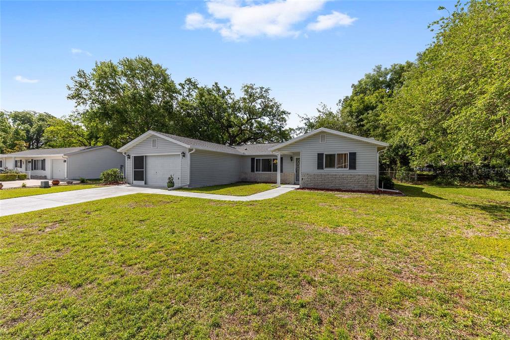 A single-story house with light gray siding, a brick facade, and an attached garage — 10622 SE 179TH LANE, SUMMERFIELD, FL