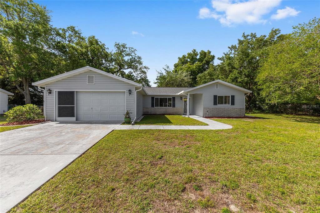 A single-story house with light gray siding, a two-car garage, and a concrete driveway — 10622 SE 179TH LANE, SUMMERFIELD, FL