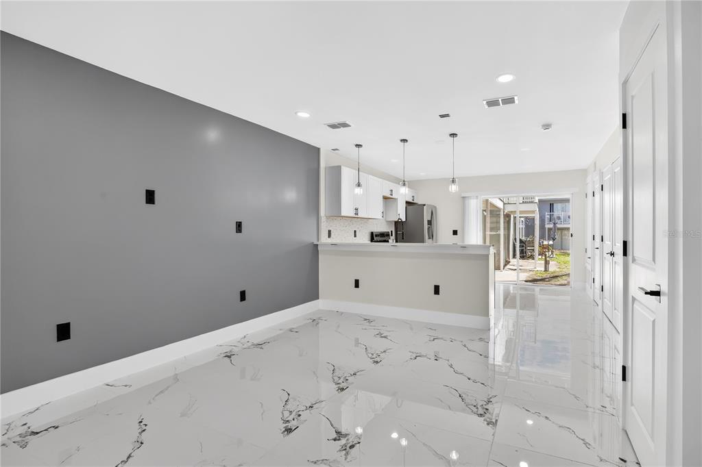 A kitchen and dining area with gray walls, white cabinets, and white marble-patterned tile floors — 3027 AARON BURR AVENUE UNIT L1, WINTER PARK, FL
