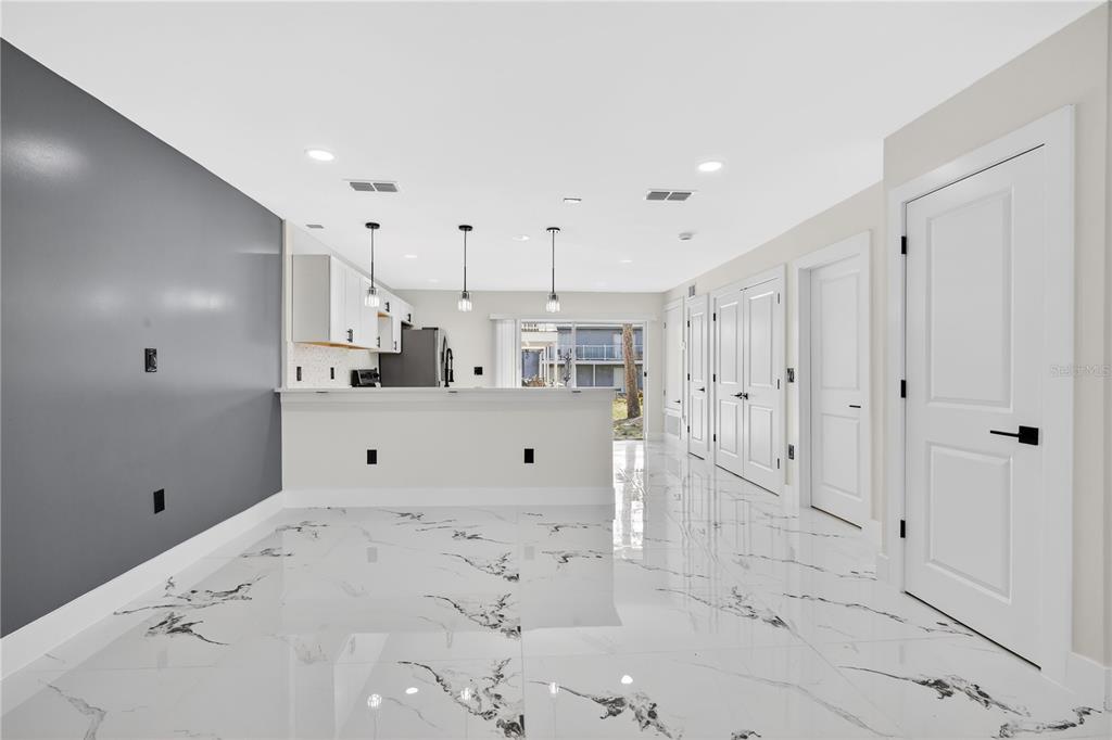 A bright kitchen and dining area features white cabinets, a breakfast bar, and marble-patterned flooring — 3027 AARON BURR AVENUE UNIT L1, WINTER PARK, FL