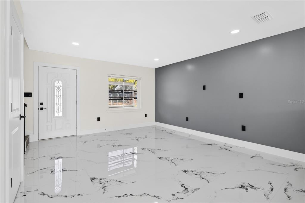 A room with white marble-patterned tile flooring, a grey accent wall, and a white door — 3027 AARON BURR AVENUE UNIT L1, WINTER PARK, FL